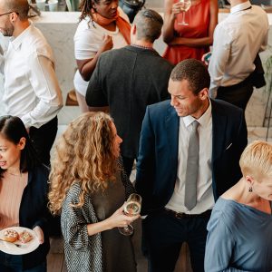 Diverse group at social event, chatting and networking. People enjoying conversation, food, and drinks. Socializing in lively, multicultural event. Diverse people socialize at social network event